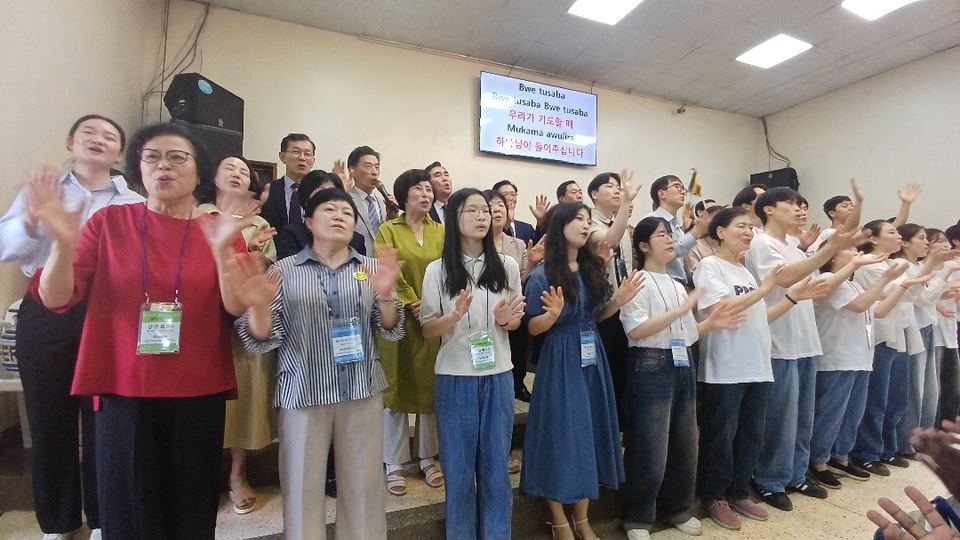 A visiting team wearing name badges worshipping together in a church hall