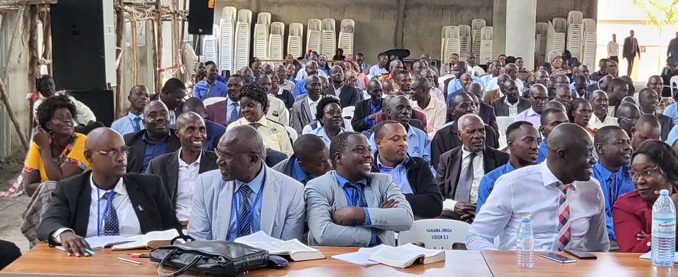 Pastors in suits seated at tables during a conference session