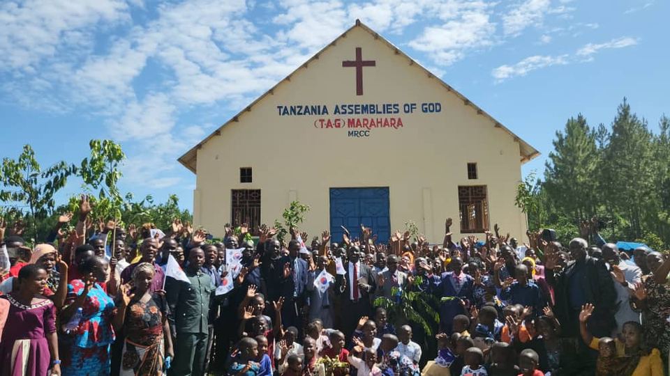 A large crowd celebrating outside a church building with a cross on its front
