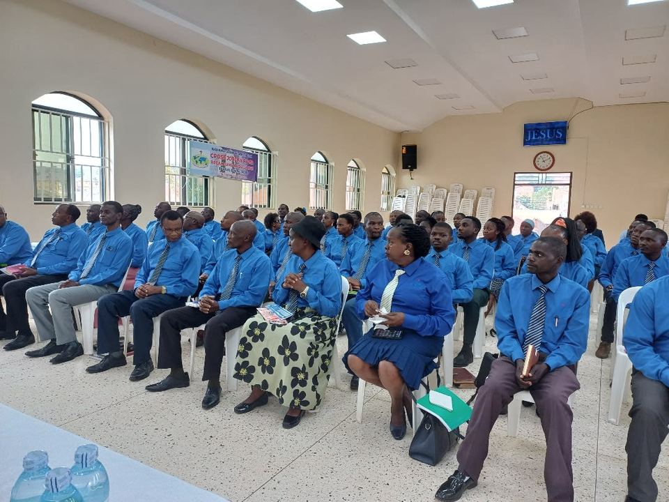 Theology students in blue shirts seated in rows in a church hall