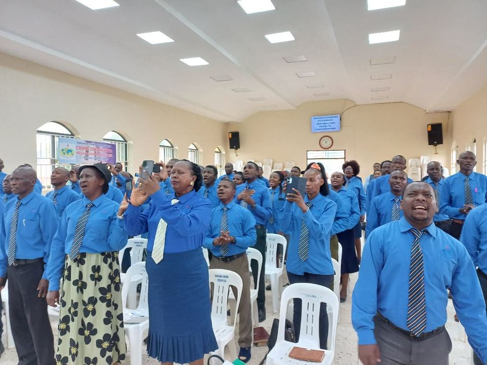 Theology students in blue shirts standing and singing in a church hall